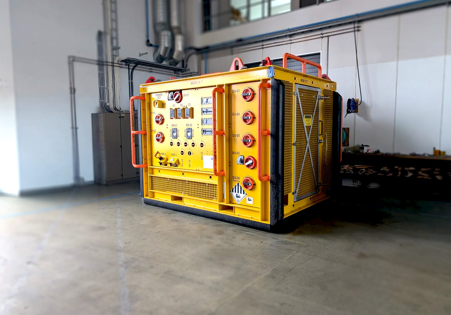Yellow container rig, -Fluid sampling skid ready for inspection placed in a storage hall.