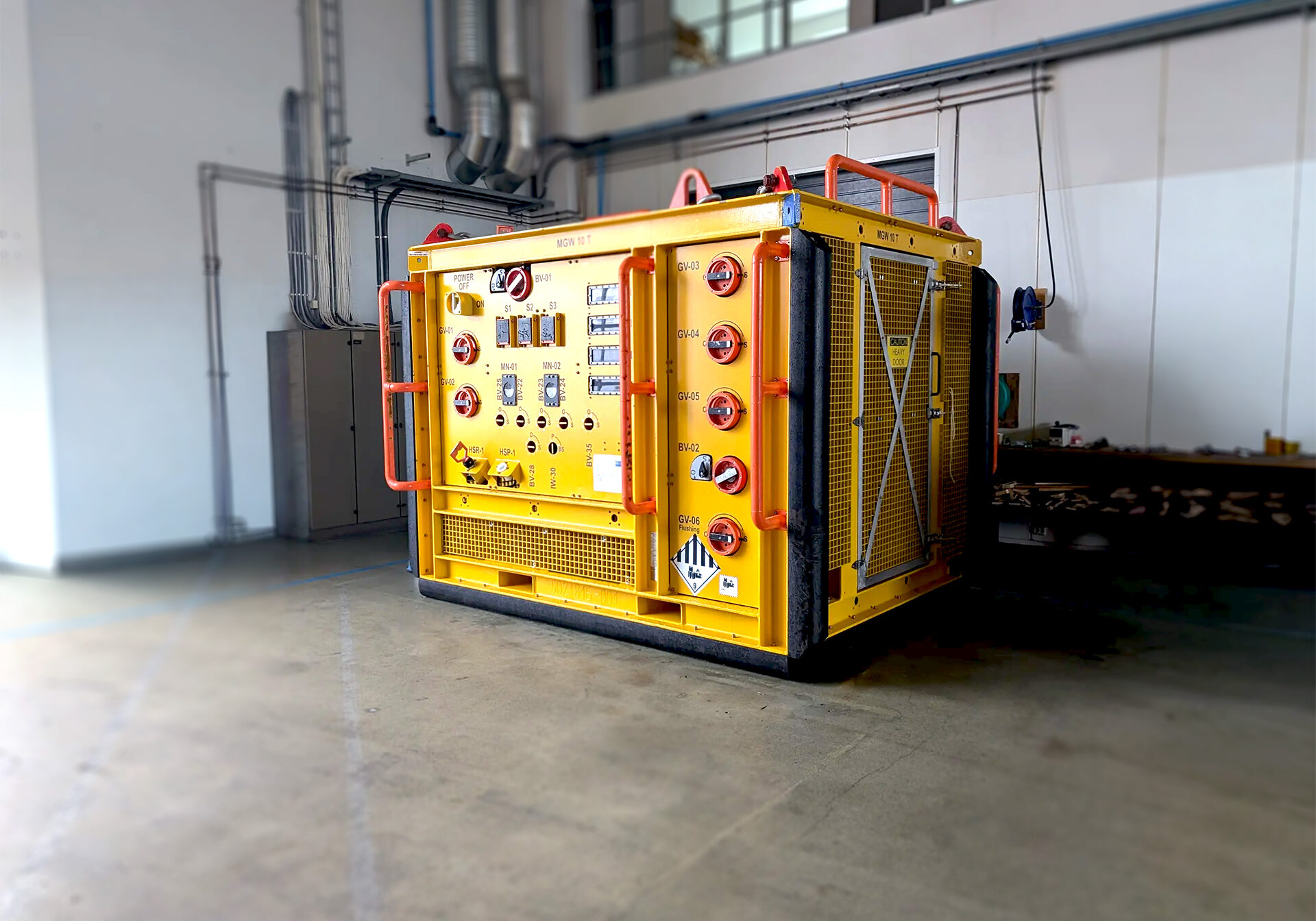 Yellow container rig, -Fluid sampling skid ready for inspection placed in a storage hall.